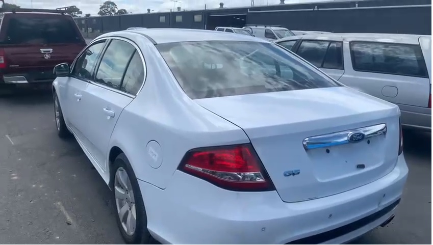 White sedan photographed from the rear in a vehicle yard