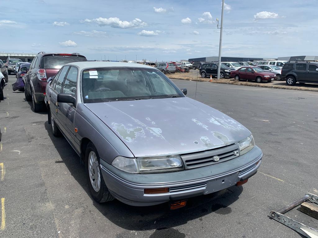 Older grey sedan in a vehicle yard