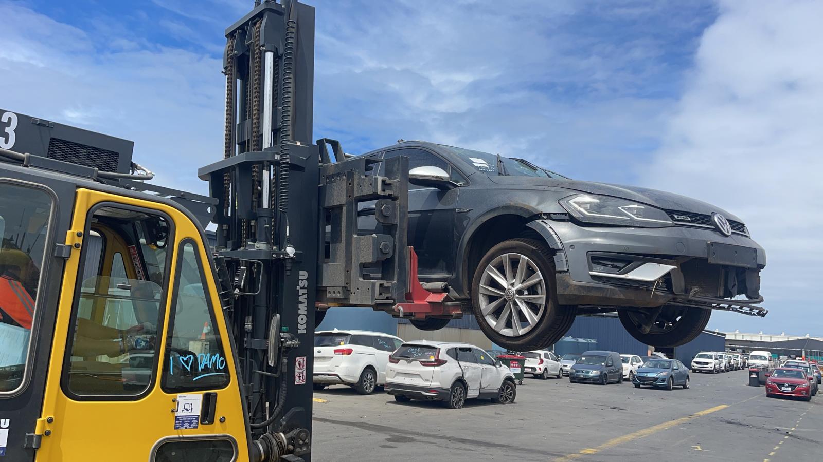 Dark vehicle raised by a forklift in a vehicle yard
